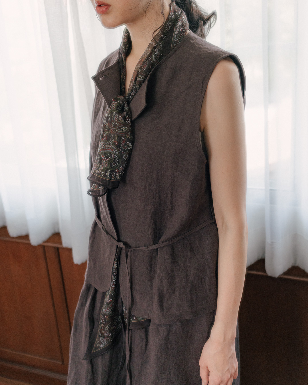 A three-dimensional silhouette that wraps around the body<br> deep brown linen belted vest